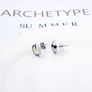 Détail de boucles d'oreilles marguerite sur carte blanche avec finitions métalliques