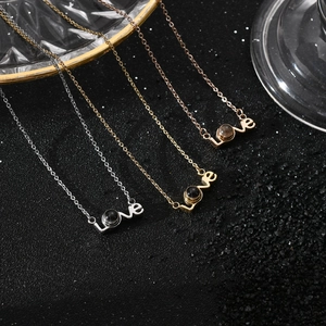 Three love projection necklaces in silver, gold, and rose gold on a textured background
