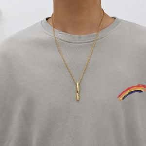 Detailed close-up of a twisted gold bar pendant with an O-chain on a male model
