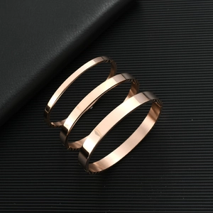 Detailed view of three rose gold stainless steel bangles stacked on a black leather surface