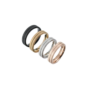Gros plan de quatre bagues en acier inoxydable mat en noir, or, argent et or rose