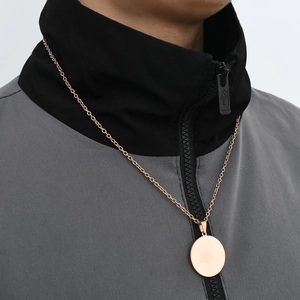 Collana con ciondolo rotondo in oro rosa lucido indossata da un modello maschile