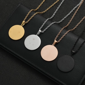 Dettaglio di ciondoli a disco tondi in finiture oro, argento, oro rosa e nero