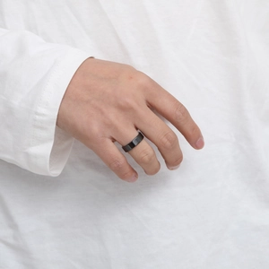 Minimalist matte black men's ring in stainless steel shown on a hand with white shirt