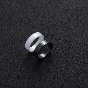 Minimalist black and white ceramic rings set on textured black background