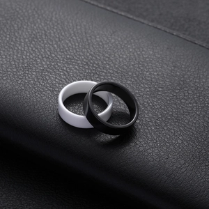 Minimalist black and white ceramic ring set on textured black leather background