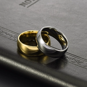 Polished gold and silver tungsten rings displayed on textured black leather surface