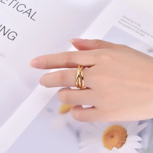 Macro shot of gold-plated triple interlocking rings on finger with magazine background