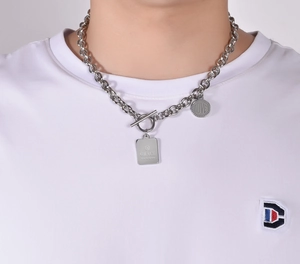 Détail du collier en acier titane argenté avec plaque carrée et fermoir à bascule