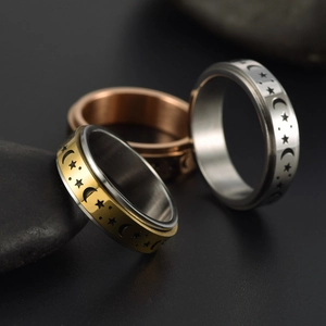Detailed view of rotating spinner rings with star and moon patterns in three metal tones