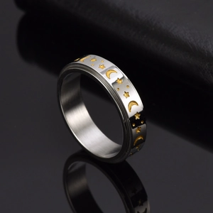 Polished stainless steel spinner ring with moon and stars patterns on black surface