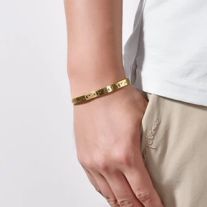 Detailed close-up of a gold open cuff bracelet with star and moon cutout engravings