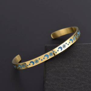 Goldener Armreif mit blauen Emaille-Mond- und Sonnenmustern auf Schmuckschatulle