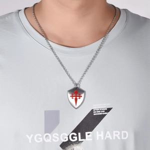 Gros plan d'un pendentif bouclier en acier titane avec le logo de la croix de Santiago