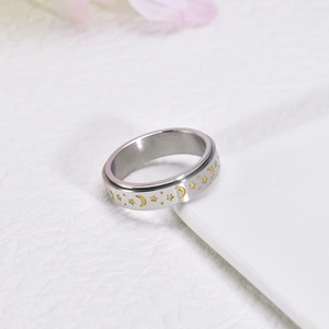 Macro shot of spinner ring with gold celestial stars and moon on silver brushed steel