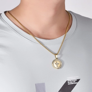 Close-up of gold crystal cross disc necklace worn by model showing jewelry scale