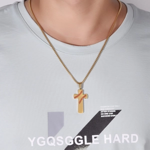 Gros plan du pendentif croix dorée avec motif couture de baseball porté par un homme