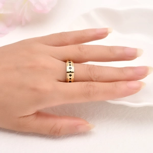 Detailed close-up of golden spinning ring with black star patterns on white ceramic