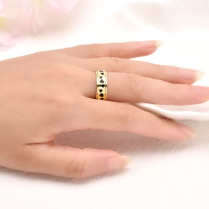 Elegant gold spinner ring with black heart patterns on a polished stainless steel band