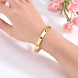 Fashion gold titanium steel star cutout bangle with clasp closure on a female wrist