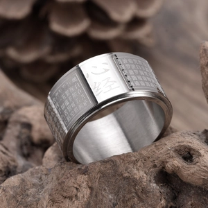 Rotating 12mm wide stainless steel Buddhist Heart Sutra ring on a natural wood base