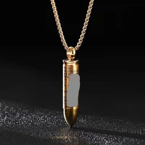 Macro shot of gold bullet pendant with engraved prayer text and box chain detail