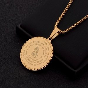 Macro shot of gold stainless steel pendant with prayer hands and engraved scripture