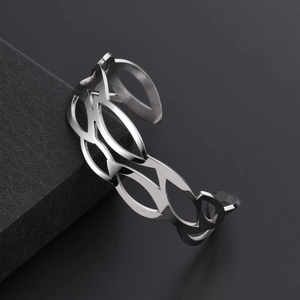 Macro detail of geometric hollow wave pattern on polished silver stainless steel cuff