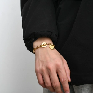 Détail d'un bracelet doré à maillons avec breloque en cœur et fermoir en T élégant