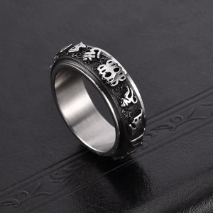 Vintage stainless steel spinning ring with embossed punk motifs on a textured display