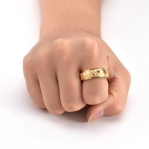 Macro view of gold stainless steel rotating ring with engraved stars on a matte surface