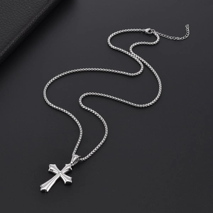 Polished silver cross pendant on a stainless steel box chain over a dark background