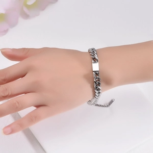 Dettaglio di un bracciale a catena cubana d'argento con piastrina ID lucida sul polso