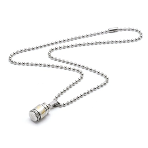 Macro detail of silver stainless steel cylinder pendant with golden Buddhist mantra engraving