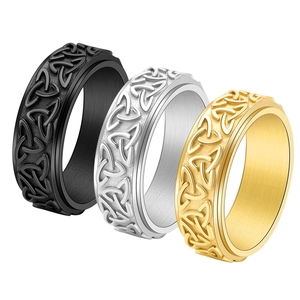 Detail of three spinner rings in black, silver, and gold with Celtic knot relief