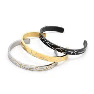 Detailed view of silver, gold, and black C-shaped open bracelets with textured wood grain