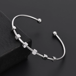 Detailed view of silver C-shaped cuff bracelet with hexagonal beads on black leather