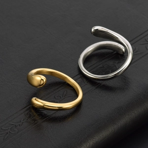 Minimalist adjustable gold and silver teardrop open rings on black textured leather background