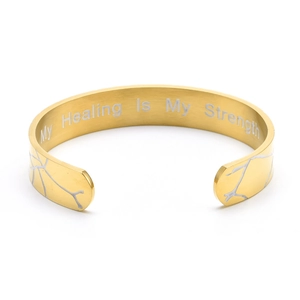 Detail view of engraved My Healing Is My Strength message on gold-tone C-shape cuff bracelet