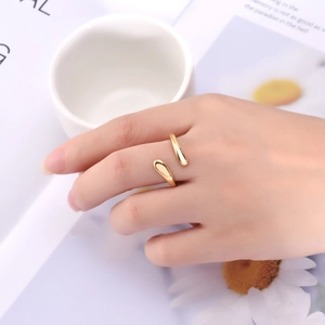 Close-up of a gold minimalist adjustable ring with teardrop ends worn on finger