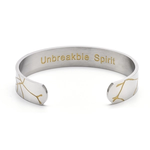 Detail view of silver C-shaped cuff bracelet with Unbreakbie Spirit gold engraving