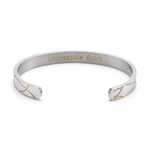 Detailed view of silver open cuff bracelet with gold cracks and Unbreakable Spirit engraving