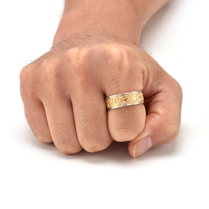 Close-up of men's stainless steel ring with golden Celtic knot inlay on hand