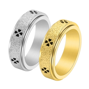 Dettaglio di anelli rotanti in acciaio inossidabile oro e argento con motivi a quadrifoglio