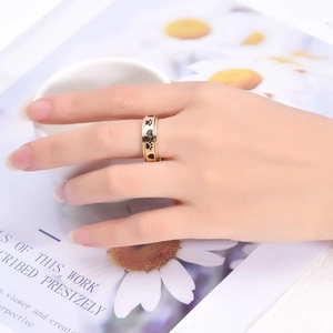 Close-up of golden wide rotating ring with black heart and paw patterns on a model's hand