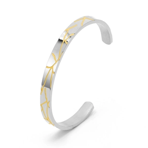 Detail of silver C-shaped cuff bracelet featuring golden wood grain crackle texture