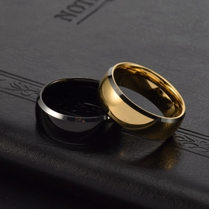Polished black and gold tungsten rings placed on a premium black leather texture notebook