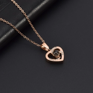 Détail macro du pendentif cœur en or rose avec pierre micro-gravée et pierres de zircon