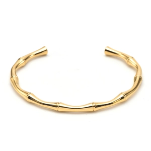 Dettaglio del bracciale rigido dorato stile bambù con finitura lucida e design aperto a C