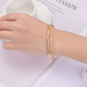 Dettaglio ravvicinato del bracciale rigido dorato a forma di bambù sul polso